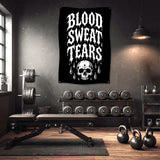 Black banner with "BLOOD SWEAT TEARS" and skull graphic hangs in a home gym.