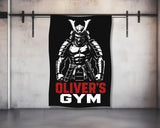 Samurai warrior graphic with text OLIVER'S GYM on a black banner hanging in a gym.