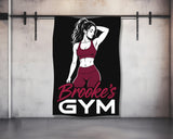 Brooke's Gym logo with a silhouetted woman on a black towel against a gym wall.