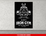 an iron gym sign hanging on a white brick wall